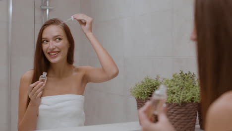 woman applying hair serum in bathroom