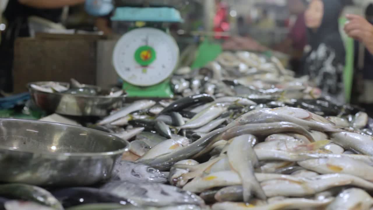 동남아시아 전통시장에서 계량기와 거래가 보이는 사람들이 있는 생선더미