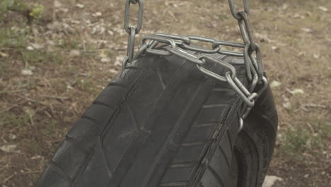 old weathered tire swing hangs on chain, close-up