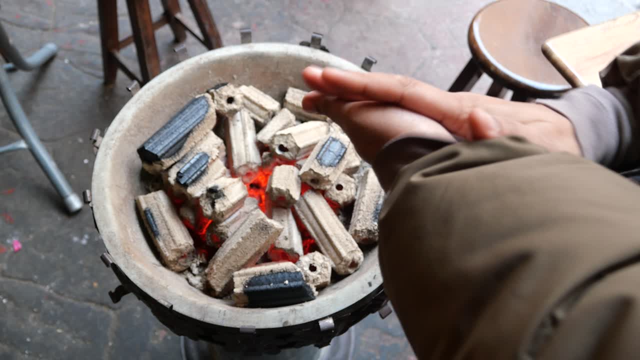 persona calentando las manos con carbón caliente