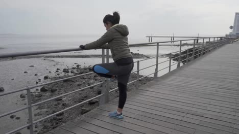 concentrated young hindu woman warming up near metal railings on wooden pier