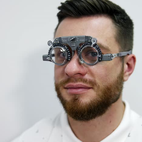 portrait of a young bearded man in testing glasses. patient examining his eyesight with optical trial frame in clinic. ophthalmology concept