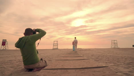 Fotograf-Fotografiert-Liebespaar-Am-Strand-Bei-Sonnenuntergang.-Fotograf-Strand