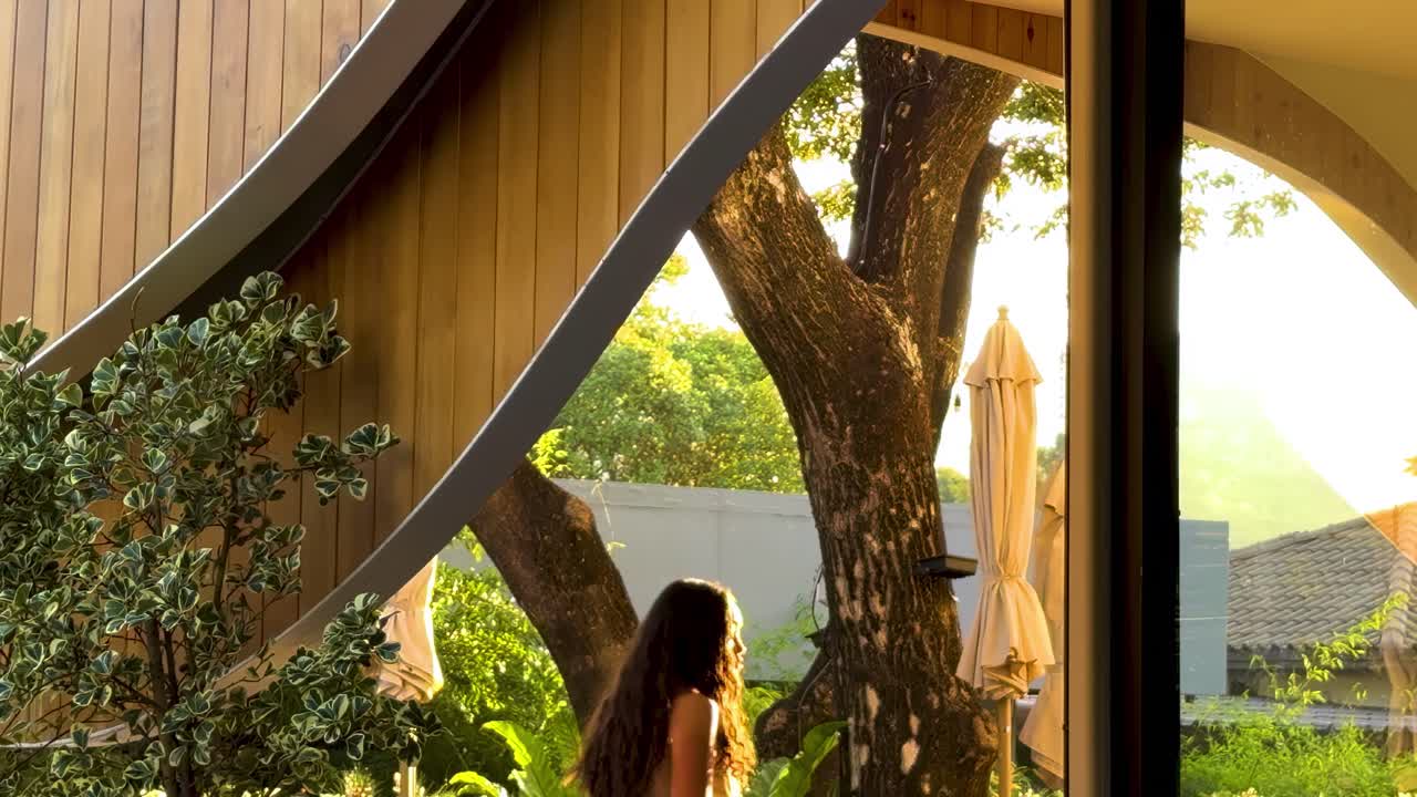 Curved wooden structure with glass and greenery