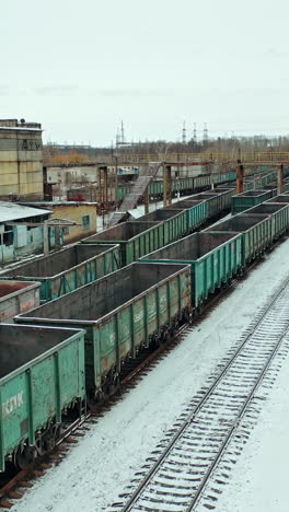 four rows of containers are located at the railway station near the state building outside the city. aerial view. vertical video