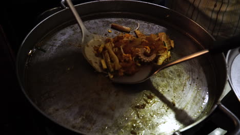 a chef making a traditional thai octopus stir fry in large stainless pan