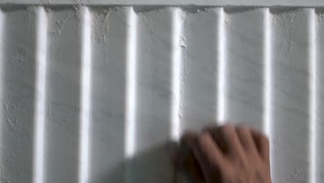 hand of a man polishing a corrugated luxury marble using a sand paper.  -medium shot