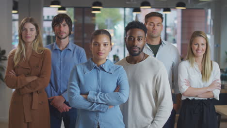 portrait of multi-cultural business team standing in modern open plan office