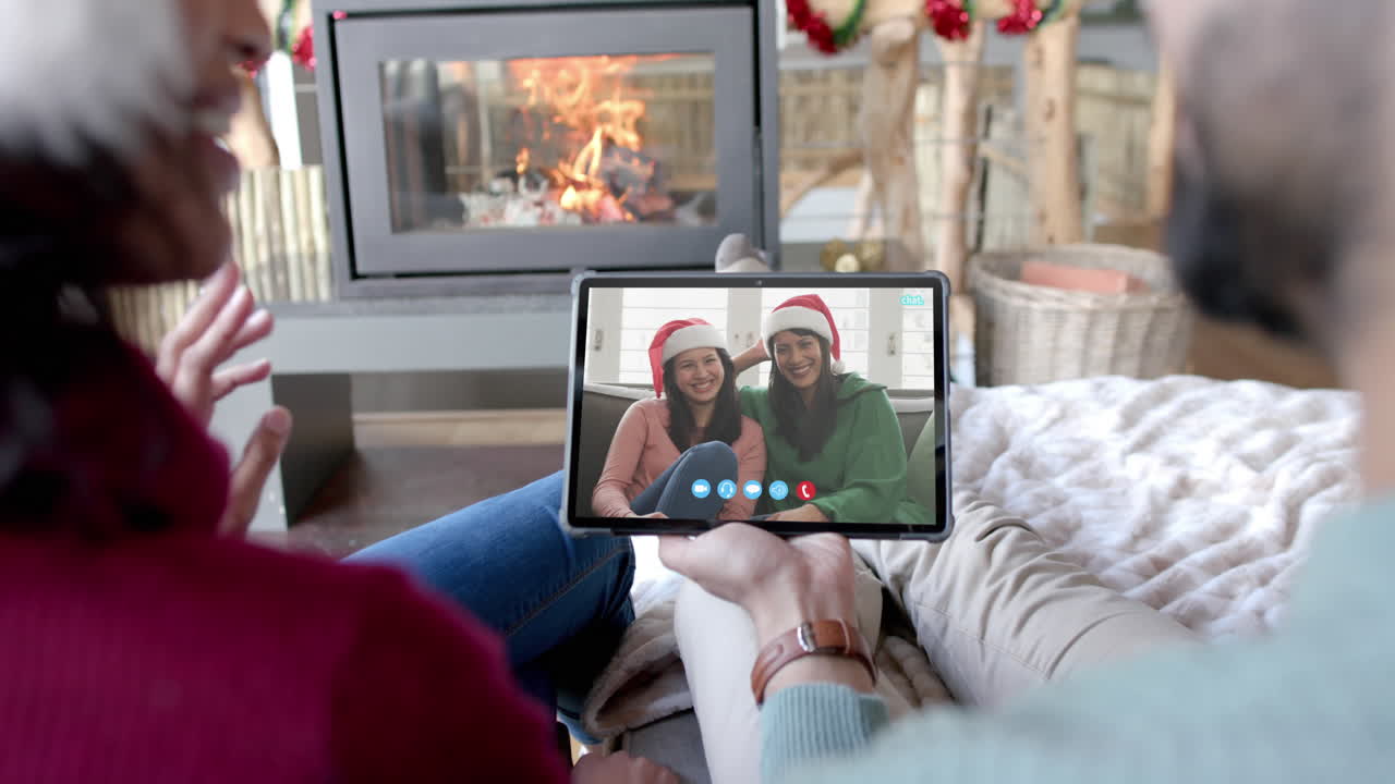 Madre e figlia felici e diverse che fanno una videochiamata di Natale su tablet, al rallentatore