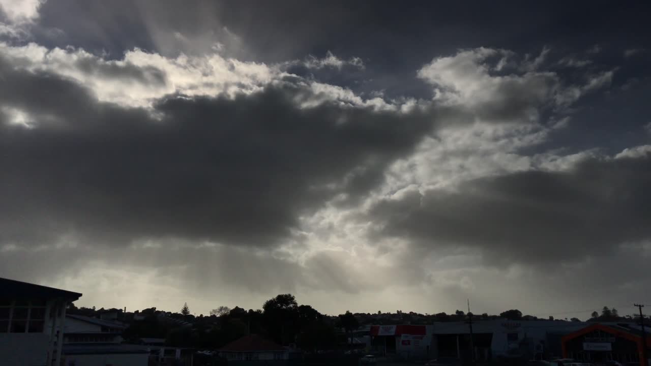 nubes ominosas de color gris oscuro con unos pocos rayos de luz solar que luchan a través del paisaje urbano gris