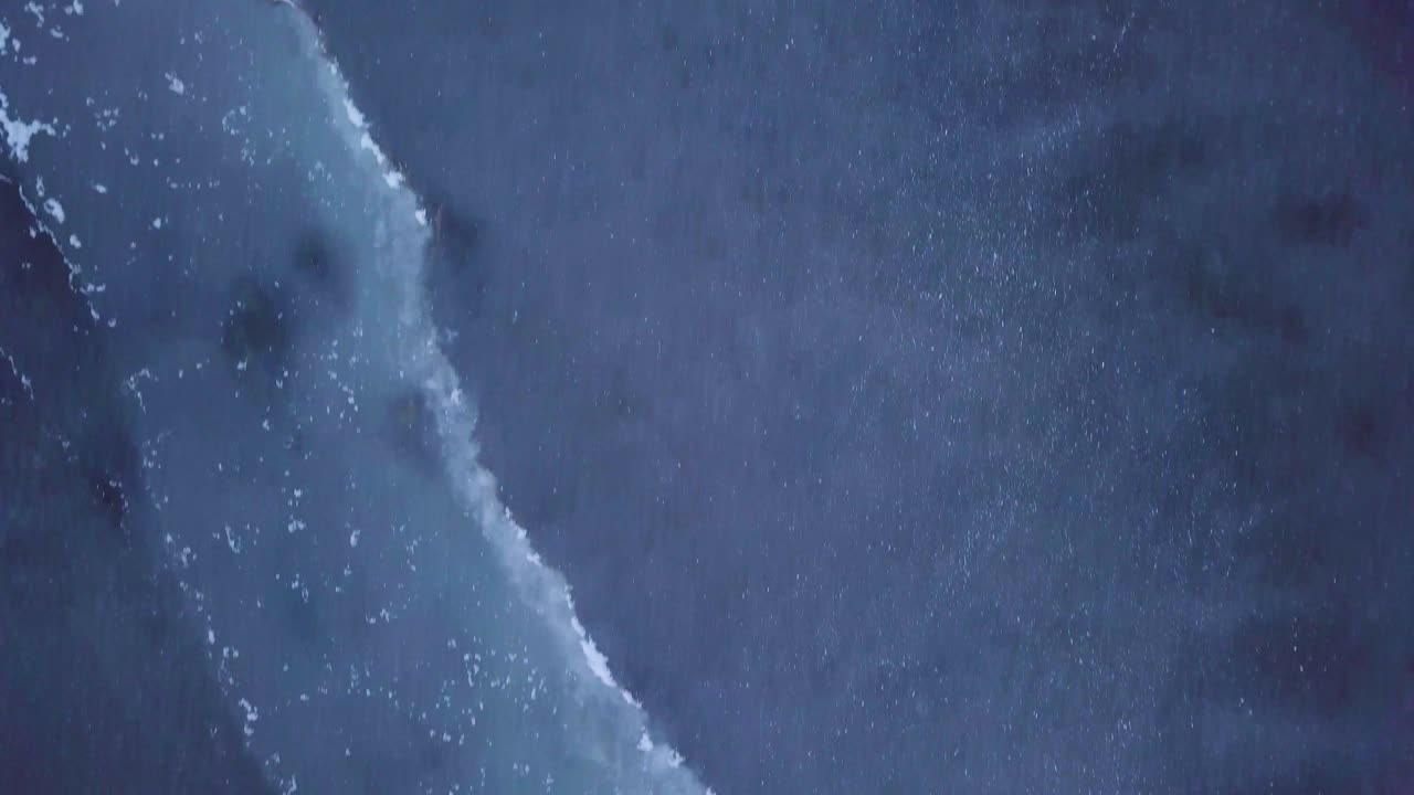 ภาพถ่ายจากอากาศของทะเลสาบ liepaja ที่แช่แข็งในช่วงฤดูหนาว น้ําแข็งสีฟ้าที่มีรอยแตก เกาะกางเขนสีเหลืองแห้ง วันฤดูหนาวที่มีเมฆภาพถ่ายโดยเครื่องบินไร้คนขับเคลื่อนที่เคลื่อนไปข้างหน้าต่ํา