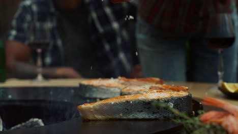 mujer chef salando pescado a la parrilla afuera