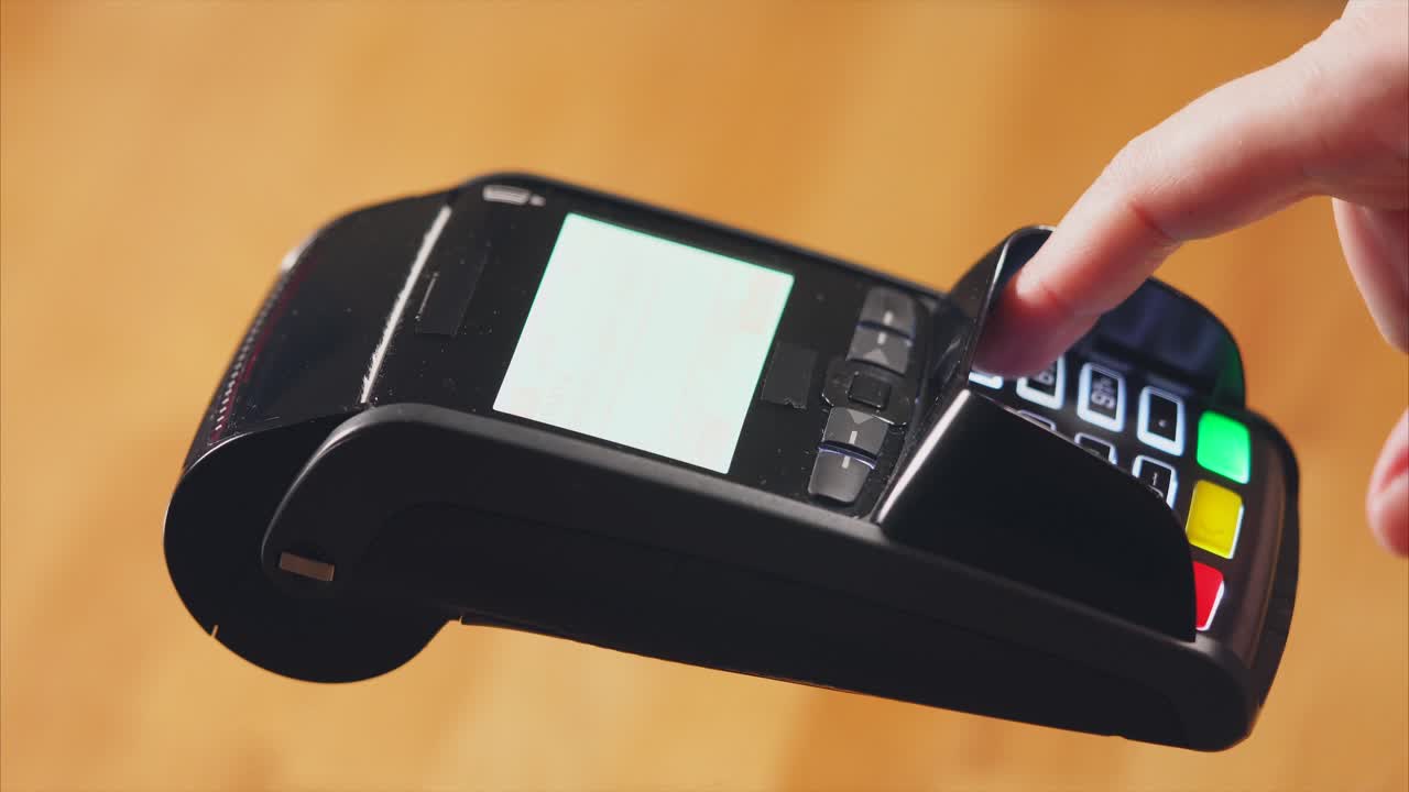 Hand holding credit card over a payment terminal