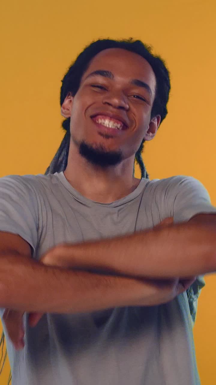 Jovem com dreadlocks mostrando emoções e gestos positivos em fundo laranja.
