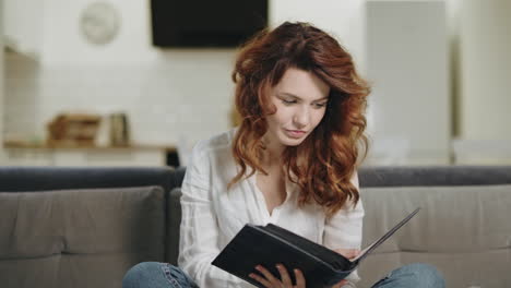 mujer bonita viendo un libro de fotos en la cocina abierta. mujer relajada sosteniendo un libro de fotos