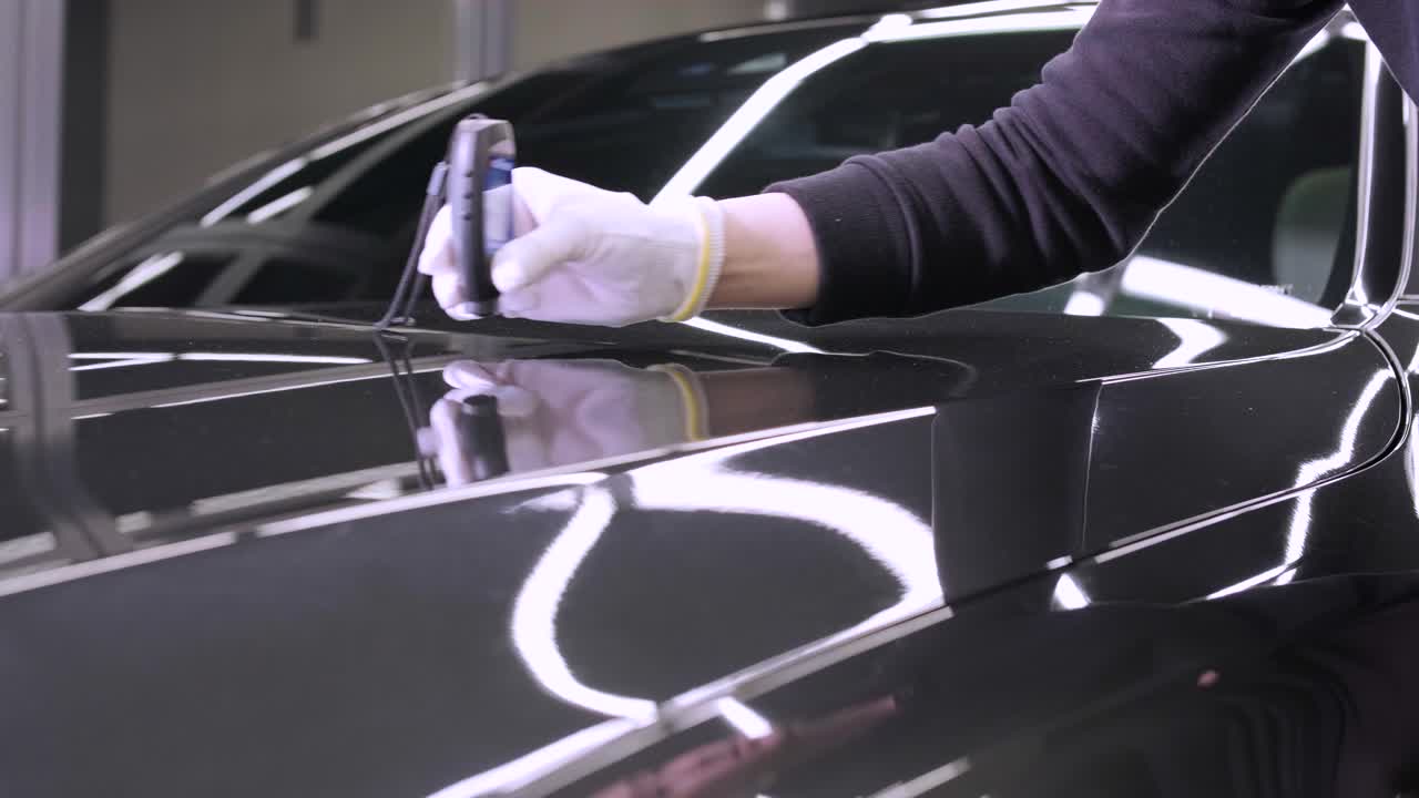 el trabajador mide el grosor del primer en la carrocería de un automóvil utilizando un medidor de grosor