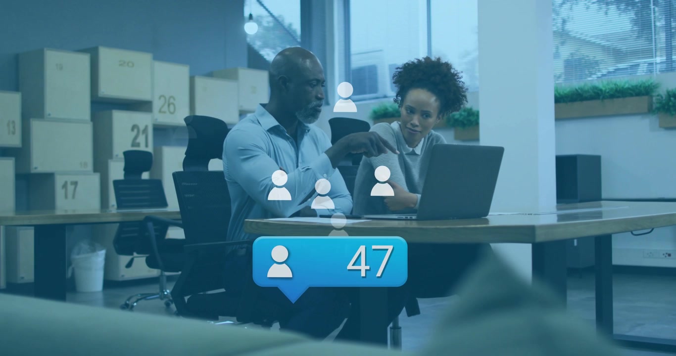 Compañeros de trabajo señalando un portátil después de que una insignia de notificación con iconos aparezca, mostrando crecimiento de marketing.