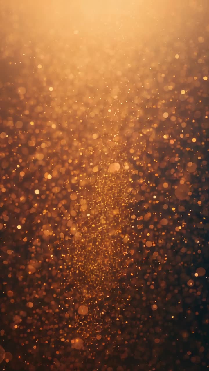 Vertical video: Glinting golden particles swirling into vortex in darkened space, with bokeh glow