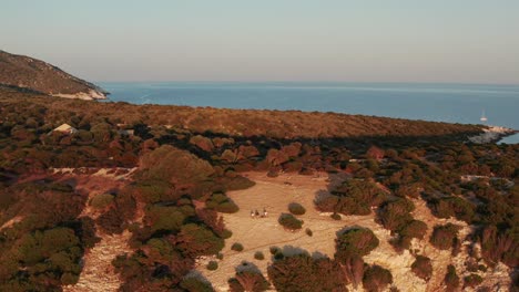 tourists at bushy deciduous forests during sunset in susac island, croatia. aerial pullback shot