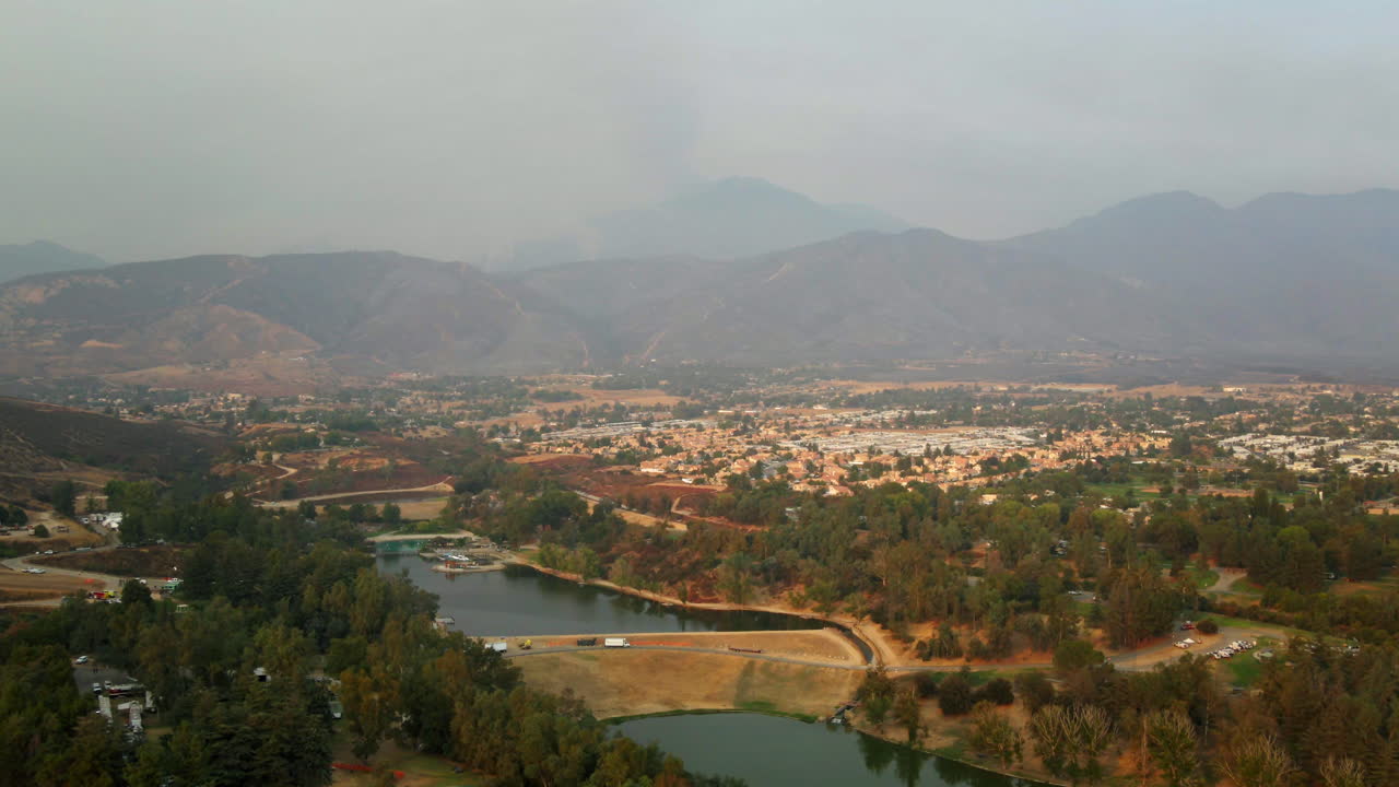 Aerial View of a Valley with a Reservoir, Residential Area, and Hazy Mountains