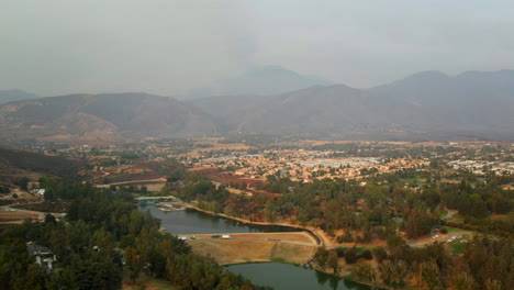 aerial view of a valley with a reservoir, residential area, and hazy mountains