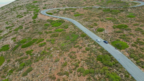 A-Smooth-Shot-Of-A-Car-Driving-Along-A-Mountainous-Road-With-Trees-And-Shrubs