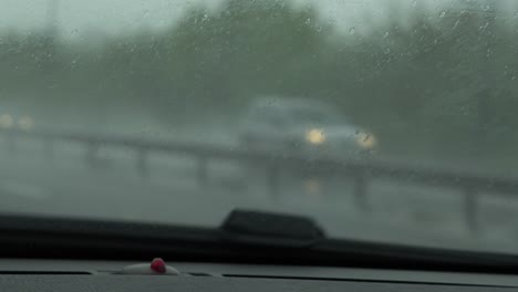 car pov driving in rain on motorway with car headlights with wing mirrors moving in slow motion
