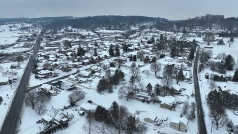 aerial view of a snow-covered rural town with roads intersecting between houses