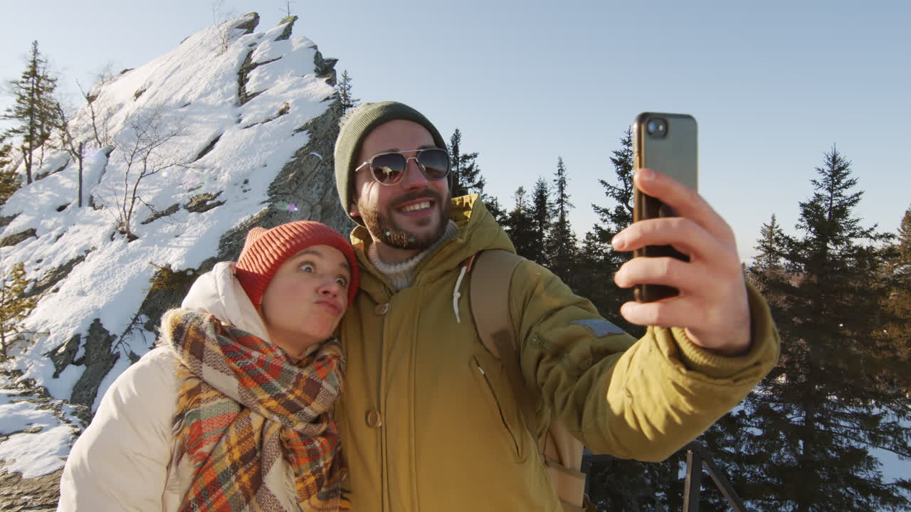 una pareja tomando una selfie en las montañas nevadas
