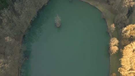 aerial drone video of a small pond in the woods on a sunny day