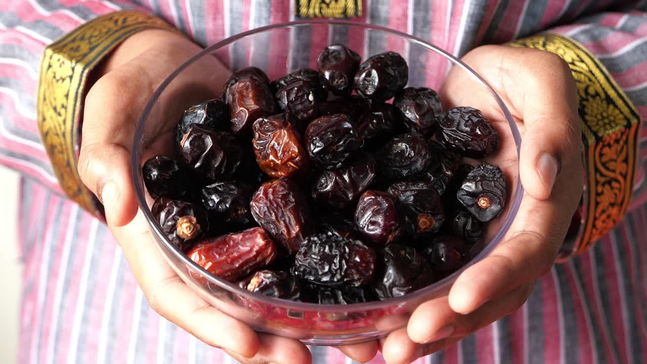 Dates in a bowl, held by hands