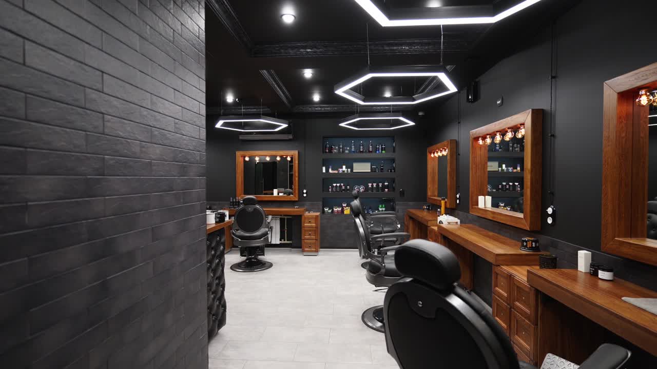 Vintage barbershop interior - movement along the chairs, wooden tables and mirrors. Stylish hair studio indoors. Stylish beauty salon design with modern lighting and lamps