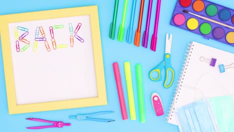 back to school title make of paper clips appear in frame surrounded with school stationery on blue theme. stop motion