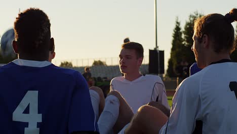 a soccer team sitting in a circle playing a fun game at sunset