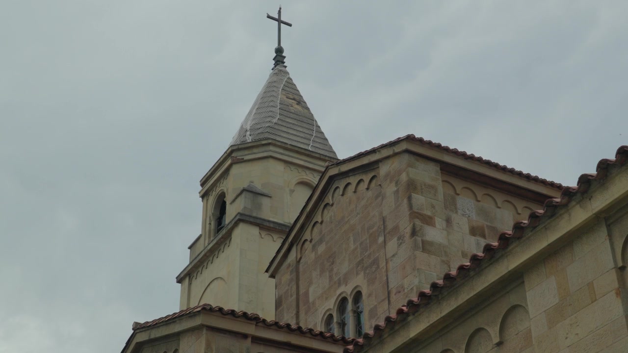 Torre sineira de pedra e telhado da histórica igreja de São Pedro contra o céu nublado