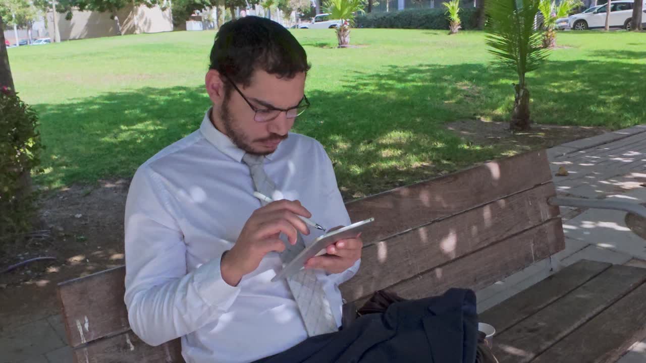 Young Man with Glasses Using a Stylus on a Tablet Computer