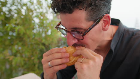man eating half of the burger ordered at the beach resort
