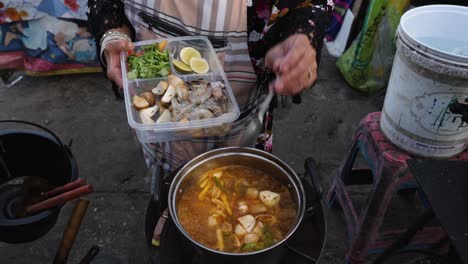 thai cook putting champignon into pot to make lovely tom yum soup