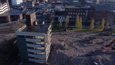 demolished multi storey car park concrete construction debris in town regeneration aerial slow left orbit view demolition