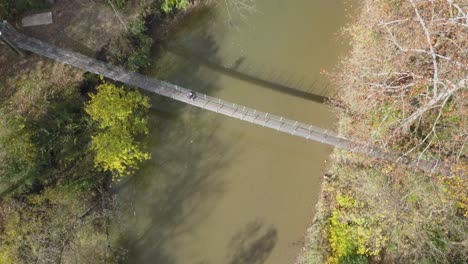 Persona-Cruza-Un-Puente-Colgante-Sobre-Un-Río-Durante-La-Temporada-De-Otoño