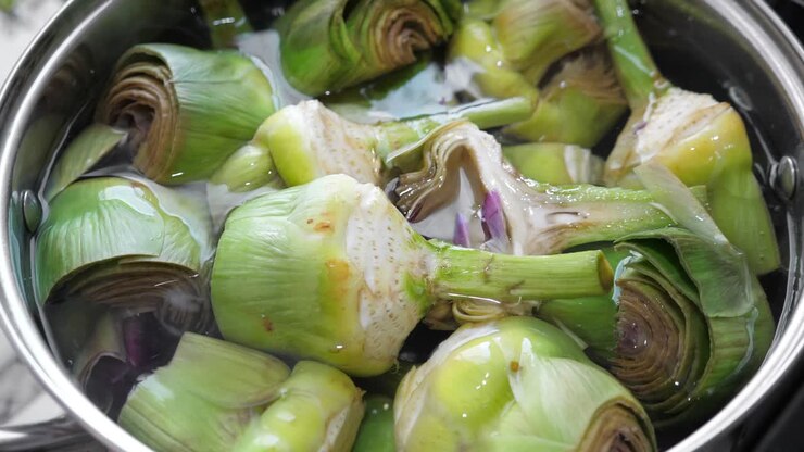 Put and cooking artichokes in saucepan, closeup in the kitchen