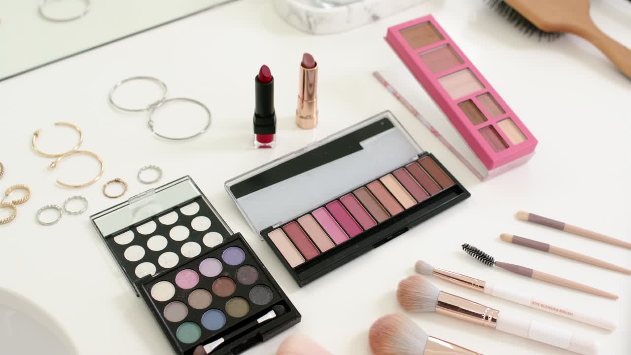 Flatlay makeup shifting as camera pushing in and adjusting focus, highlighting palettes and brushes