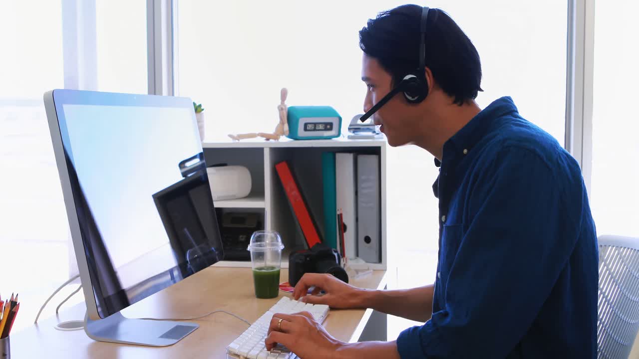 Male executive in headset working over computer at his desk 4k