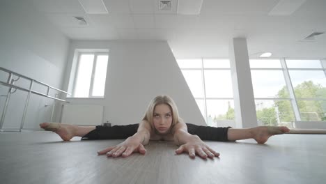 fit girl in black clothes performing contemporary. female dancer shows flowing motions, body and hands waves at white room. modern ballet dance choreography. young woman is moving smoothly