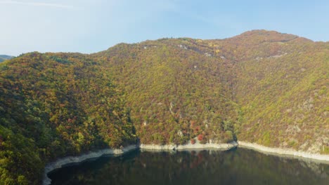 Reflejo-De-Agua-Del-Bosque-De-Montaña-Con-Colores-Otoñales,-Panorámica-Aérea-Hacia-Arriba