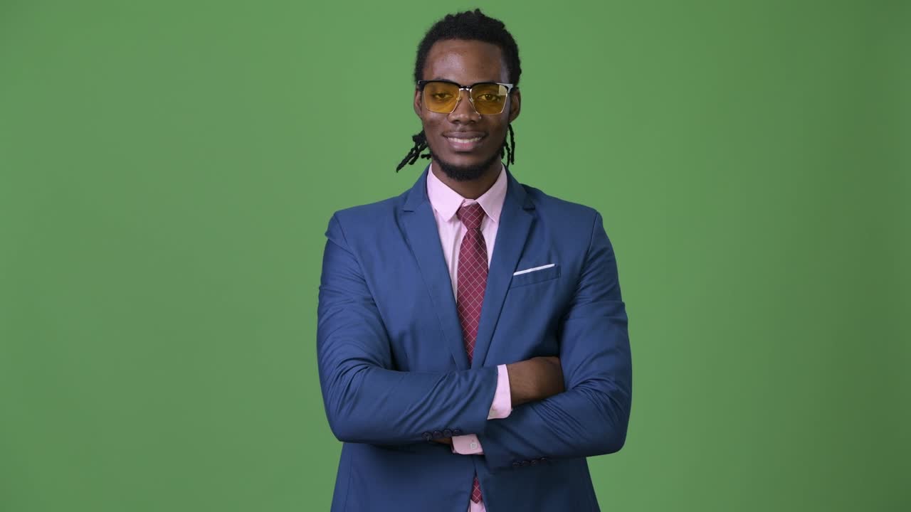 Giovane e affascinante uomo d'affari africano con dreadlocks su sfondo verde