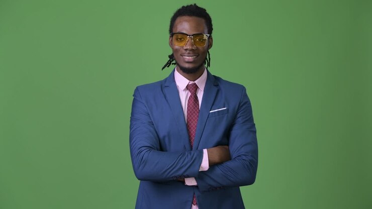 Giovane e affascinante uomo d'affari africano con dreadlocks su sfondo verde