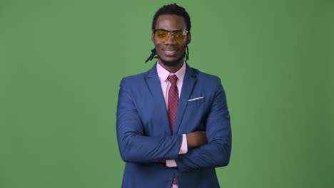 young handsome african businessman with dreadlocks against green background