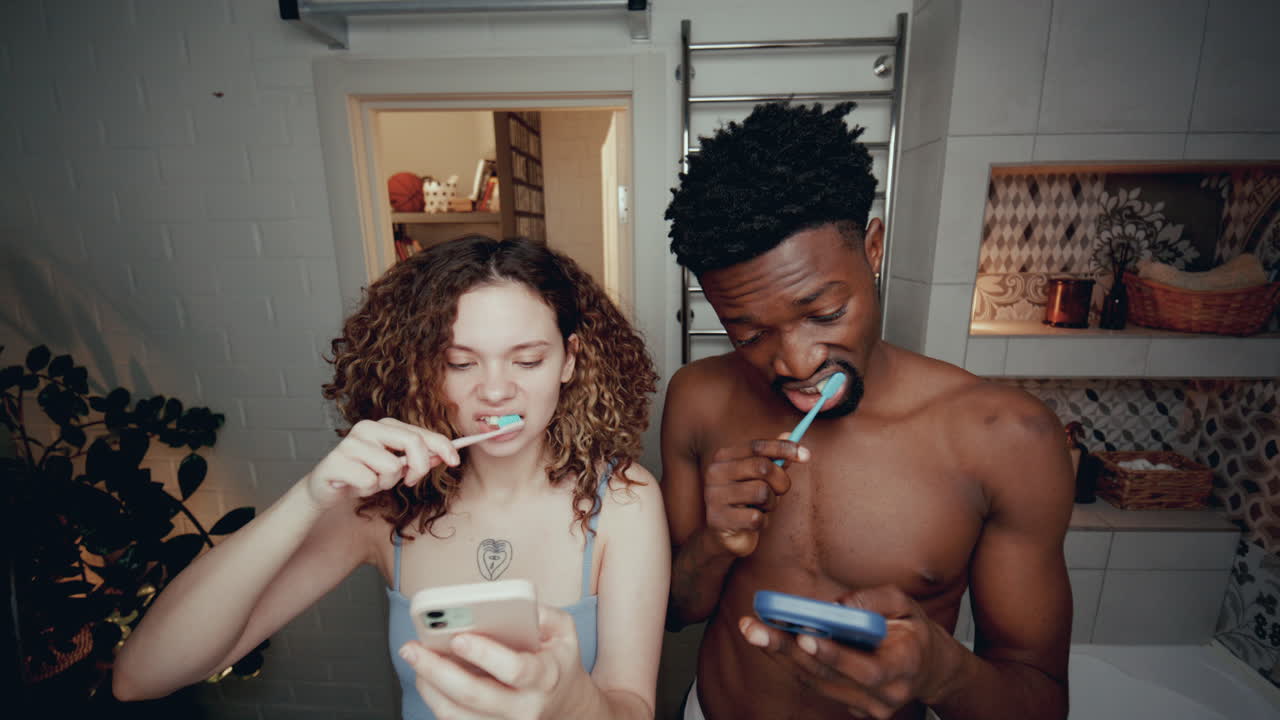 Young Couple Glued to Their Phones Brushing Teeth in Bathroom