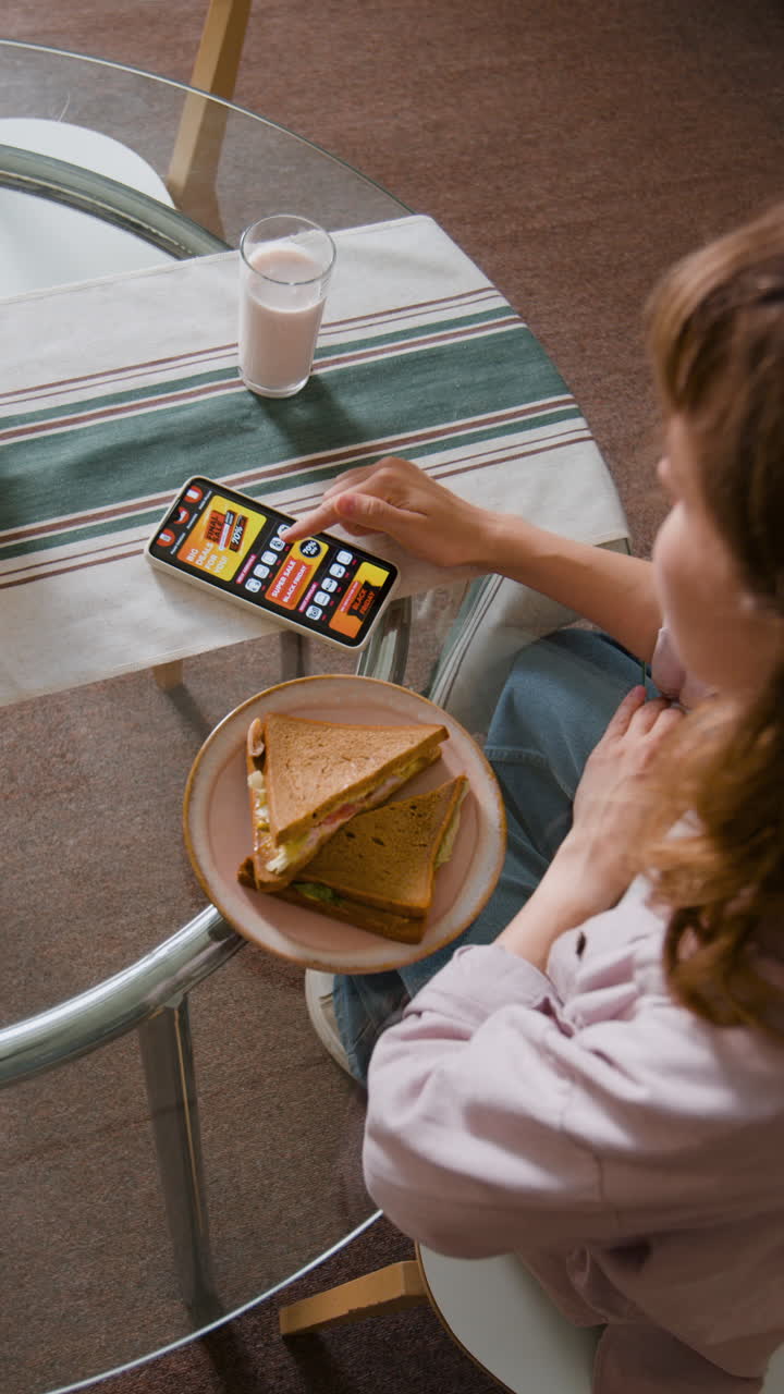 Person using phone while eating a sandwich